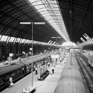 881976 Gezicht op de perrons onder de eerste perronkap van het N.S.-station Amsterdam C.S. te Amsterdam.